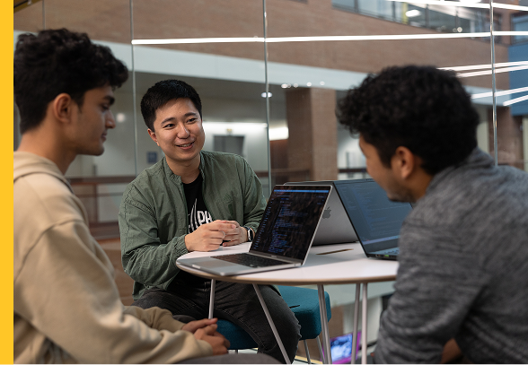 A group of people sit at a small table with laptops on ASU Tempe campus.